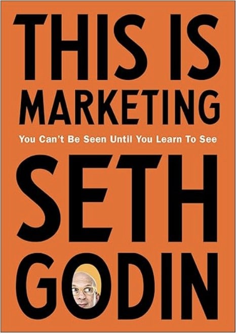 Omslag van "This Is Marketing" door Seth Godin, met opvallende zwarte tekst op een oranje achtergrond en een kleine afbeelding van de auteur in de linker benedenhoek. Deze stijl doet denken aan een boek dat wellicht de aandacht trekt van iemand die op Snel Online surft.